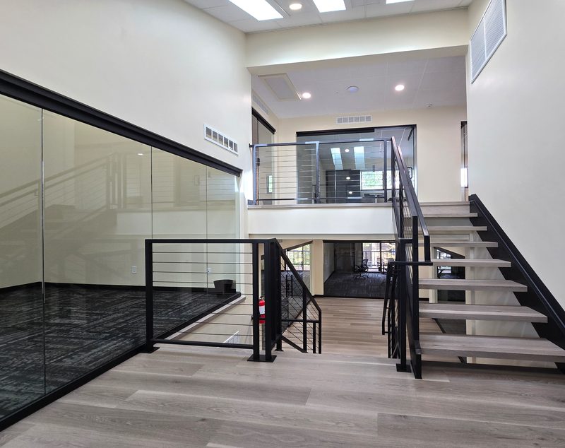 Two levels of glass offices and the central stair at ZipDesk Coworking