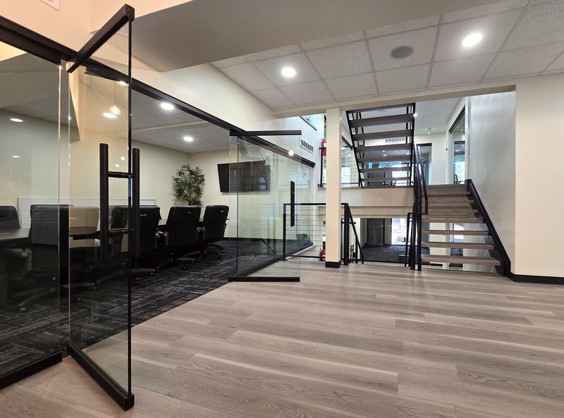 Glass office doors beside the central staircase at ZipDesk Coworking